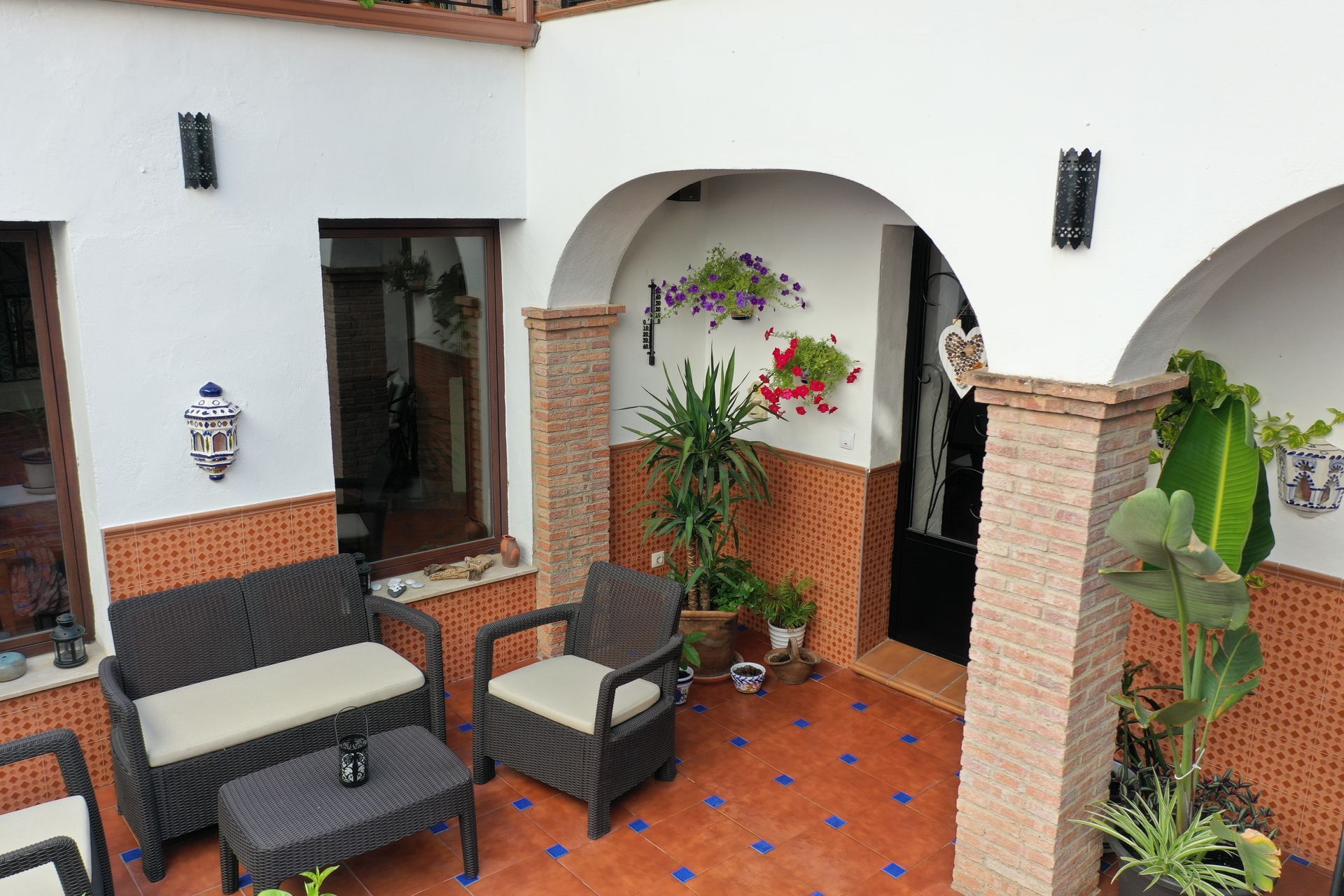 A patio with wicker furniture and potted plants