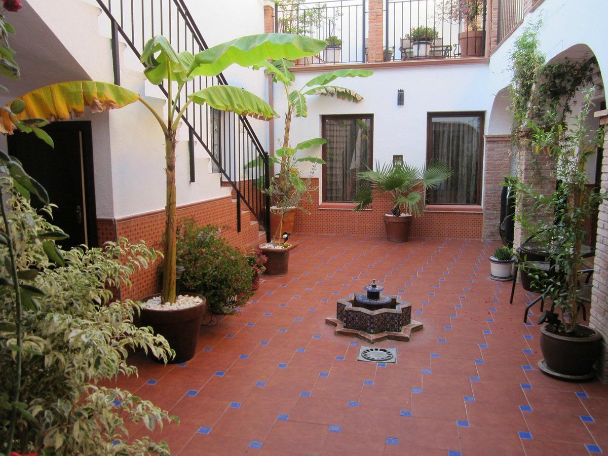A courtyard with potted plants and a fountain in the middle