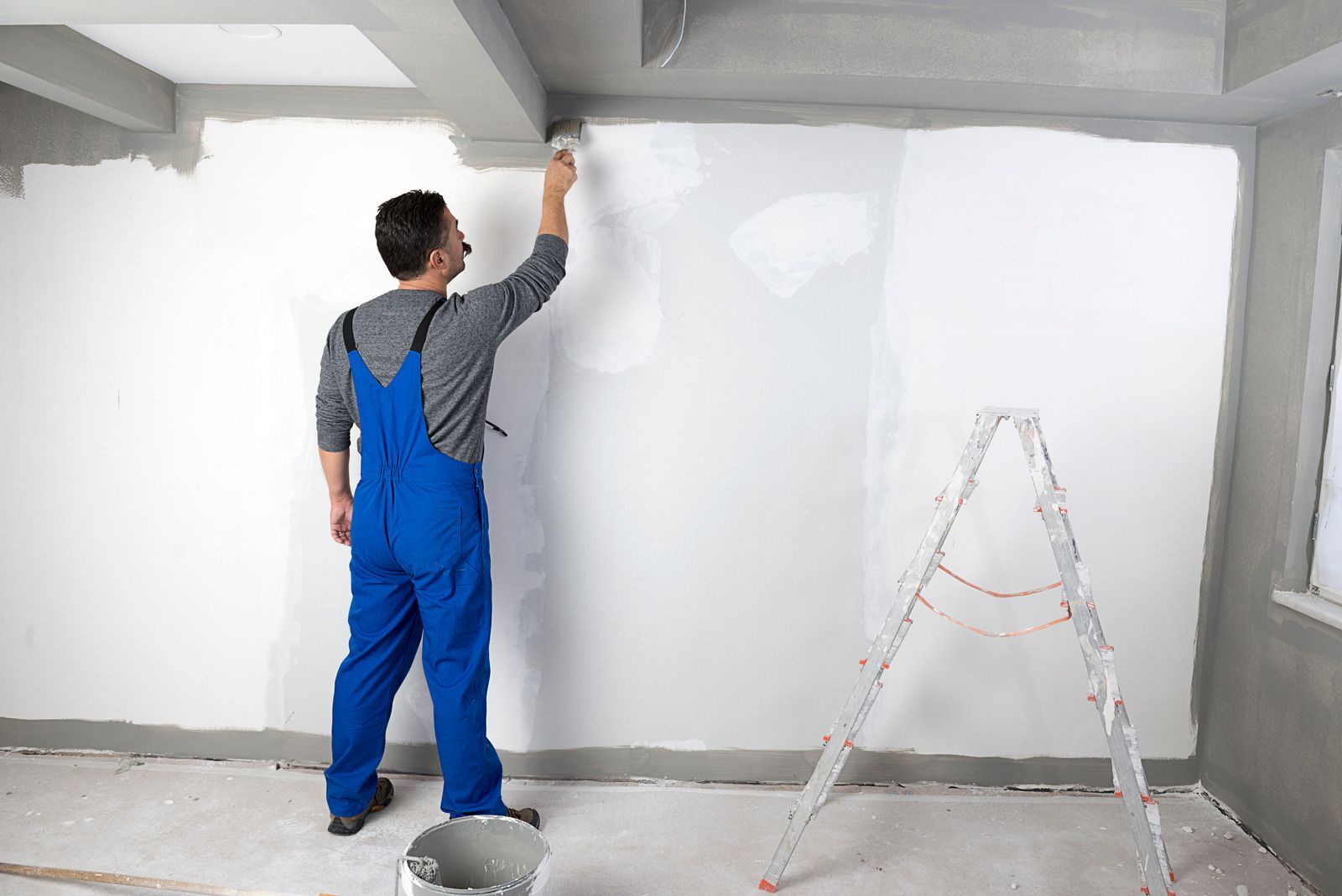A man is painting a garage door with a brush.