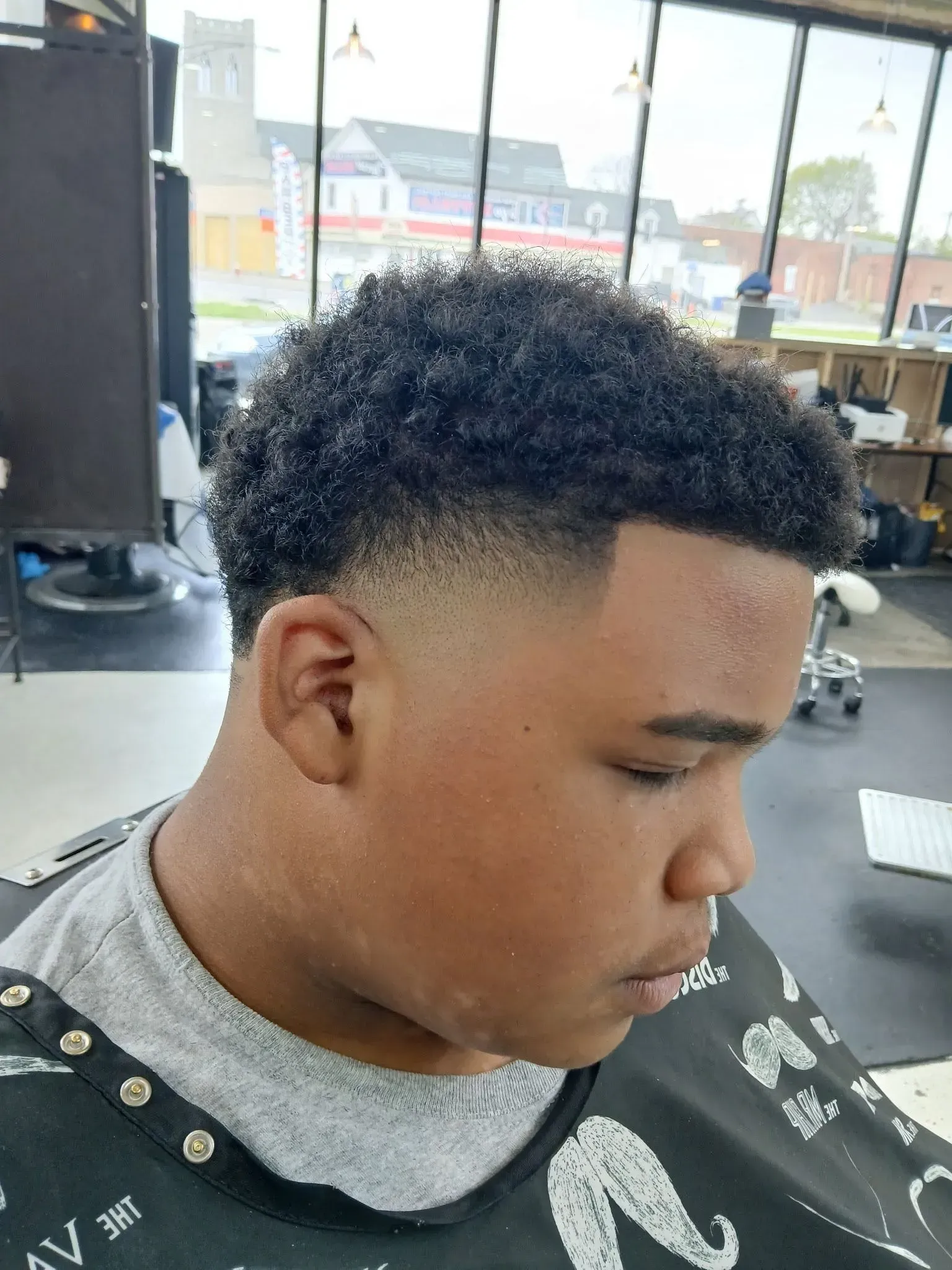 A young man is getting his hair cut at a barber shop.