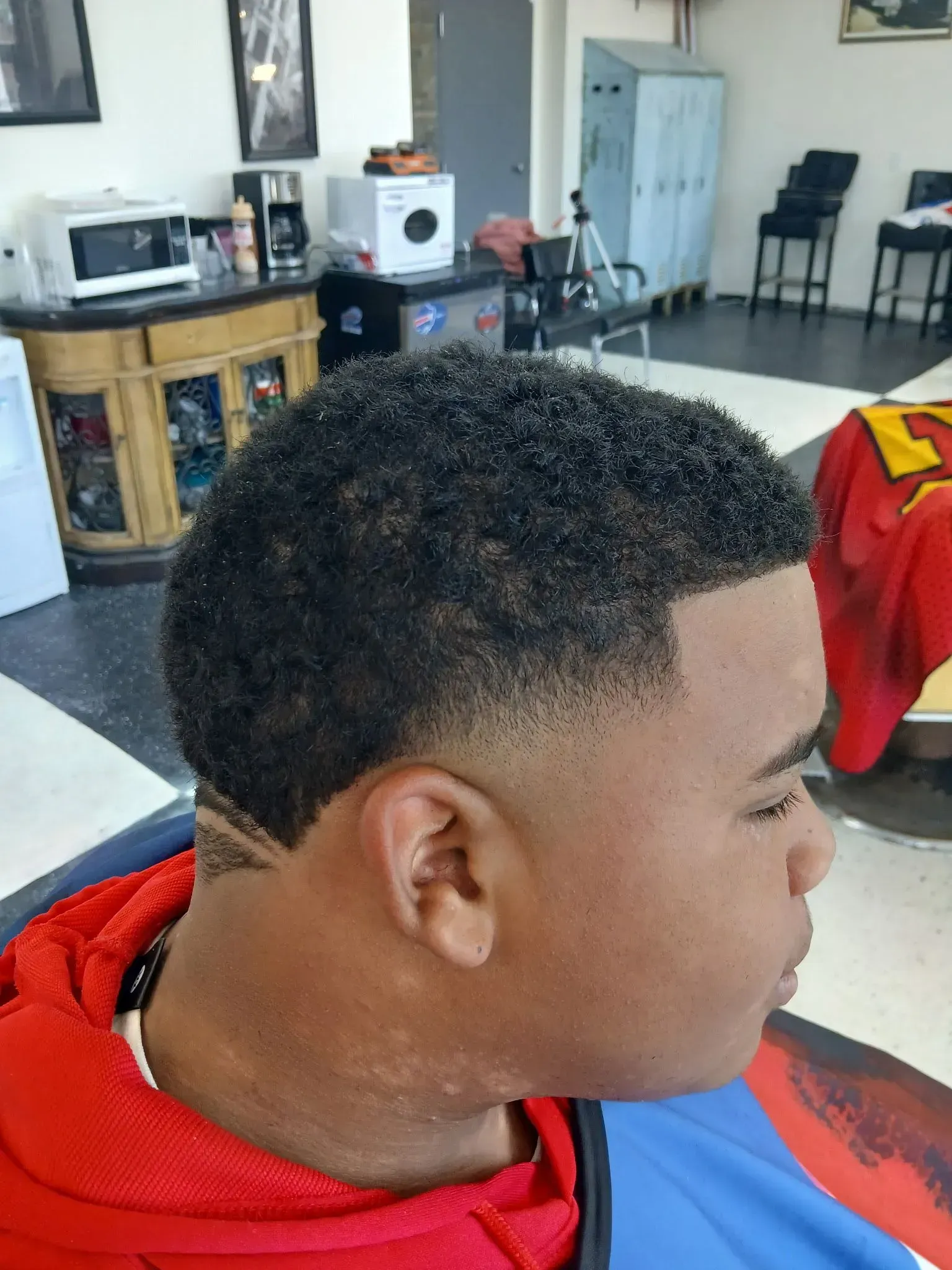 A man is getting his hair cut at a barber shop.