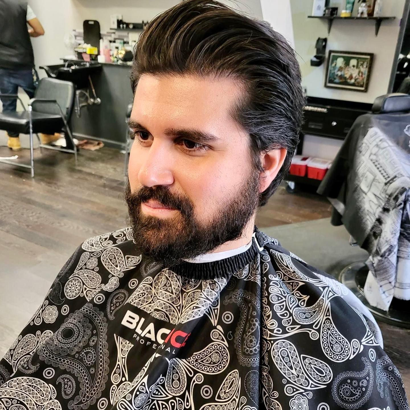A man with a beard is getting his hair cut at a barber shop