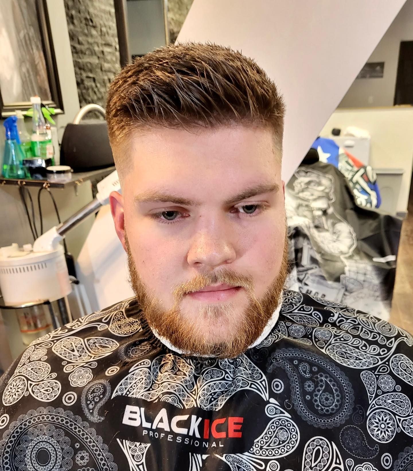 A man with a beard is getting his hair cut at a barber shop.