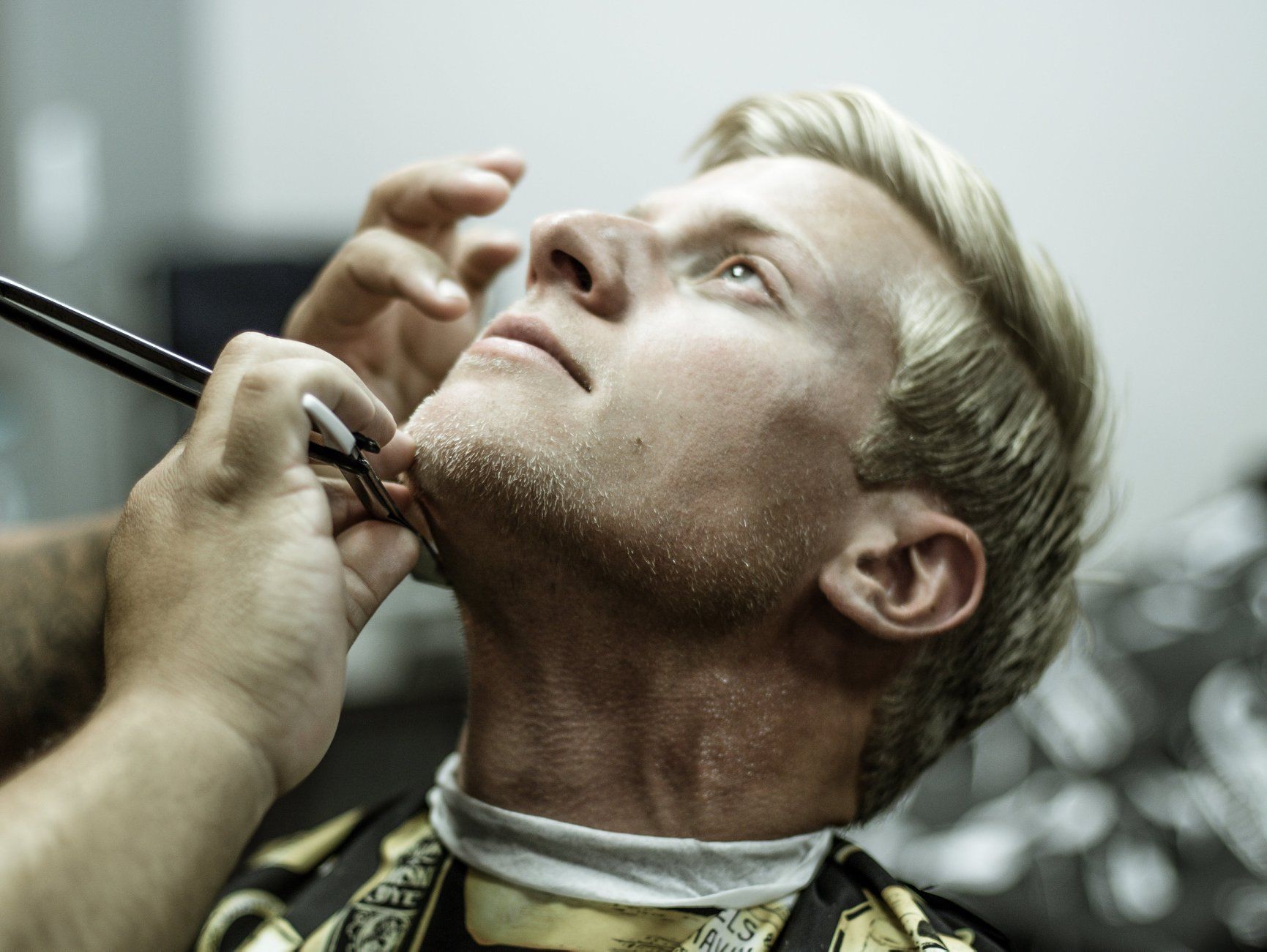 A man is getting his beard shaved by a barber.