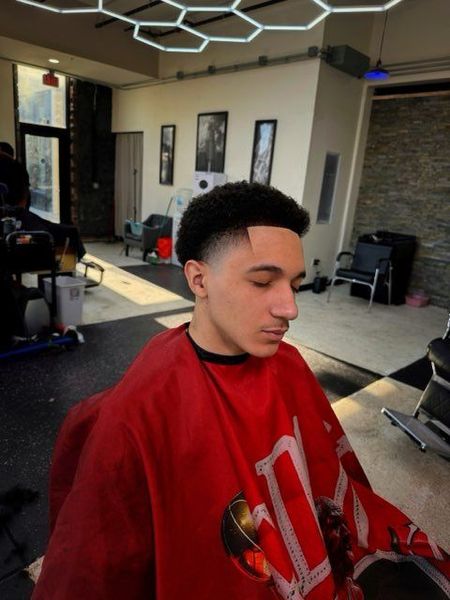 A man is getting his hair cut by a barber in a black and white photo.