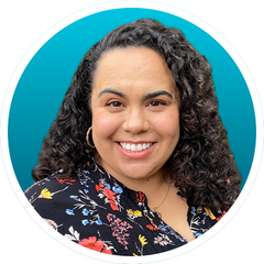 Smiling woman with curly hair in a floral top against a teal background