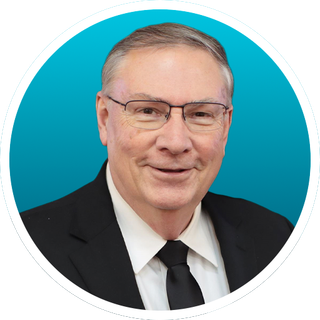 Portrait of a man in a suit and glasses against a teal background