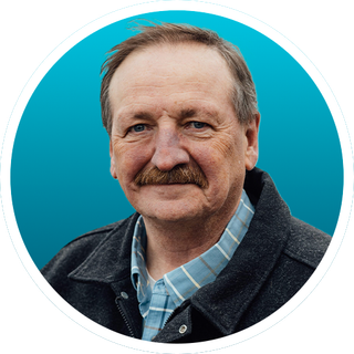 Portrait of a smiling man in a jacket against a teal background