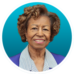 Smiling woman portrait on teal background, wearing a purple jacket and striped shirt