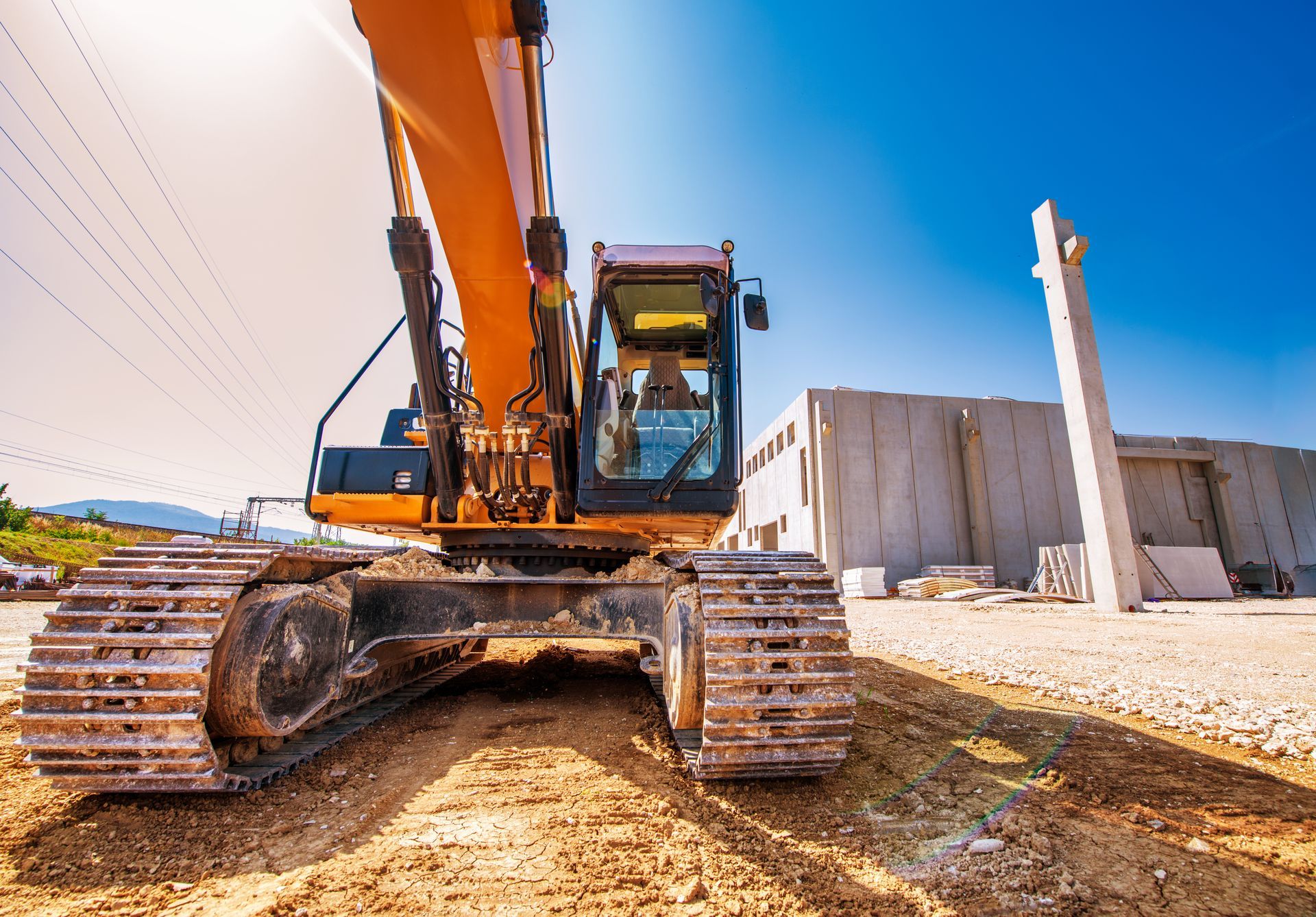 A large excavator is parked in a dirt lot in front of a building.