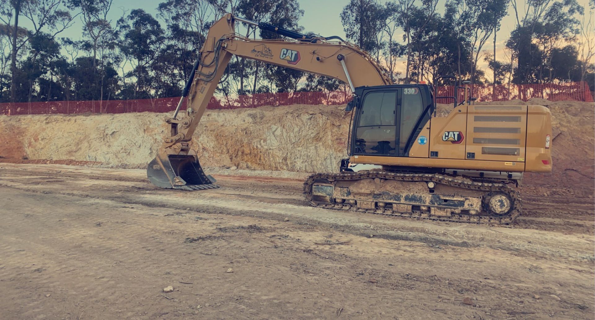 A large yellow excavator is sitting in a dirt field.