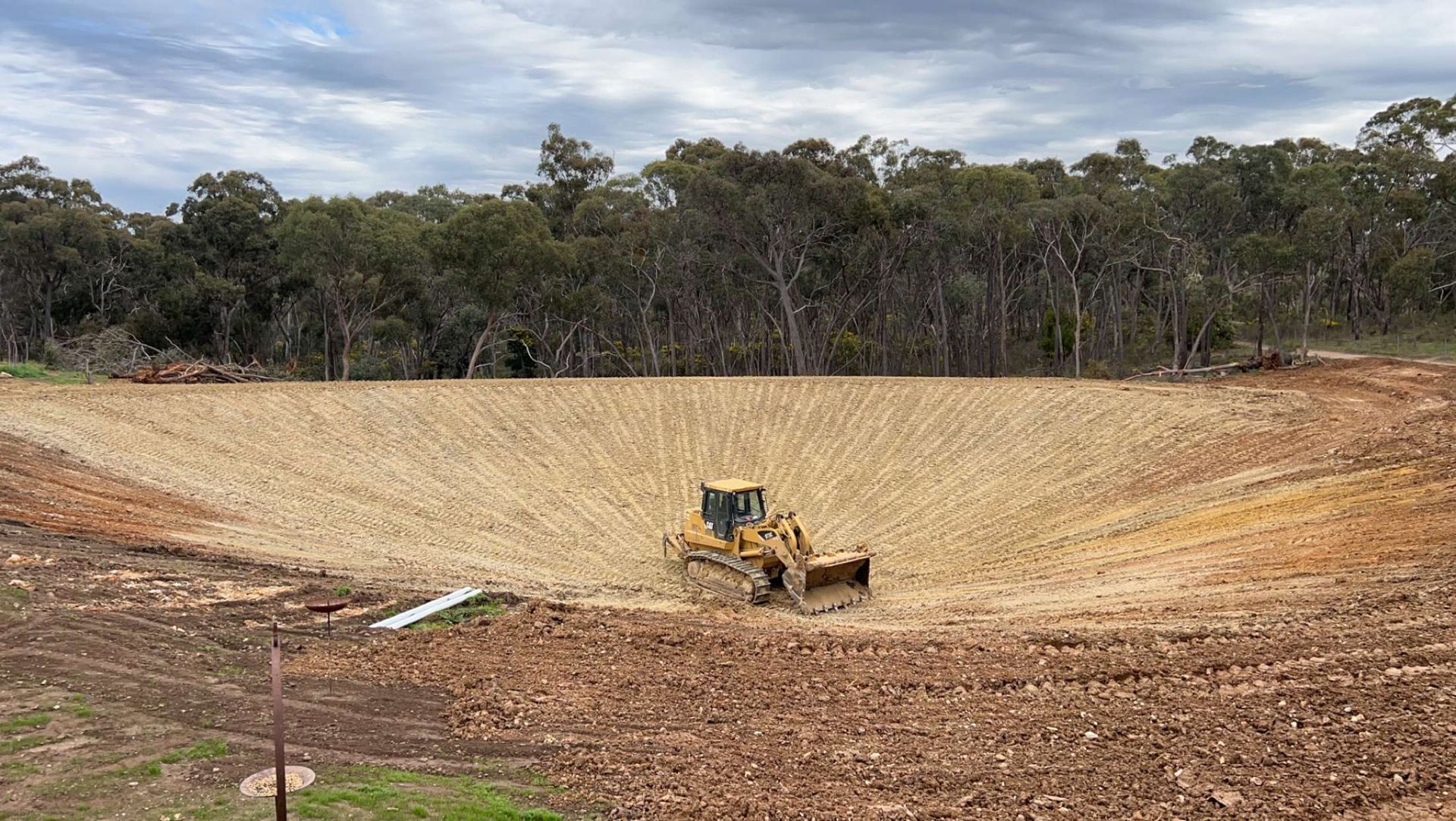 A bulldozer is sitting in the middle of a dirt field.