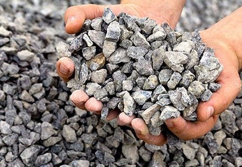 a person is holding a pile of gravel in their hands .