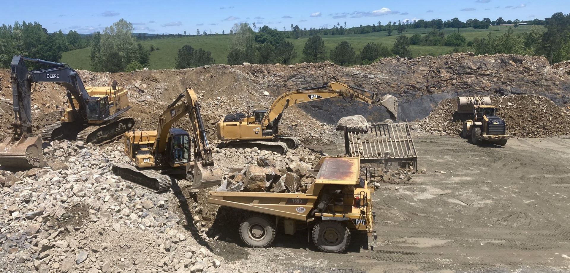 a group of construction vehicles are working in a rock quarry