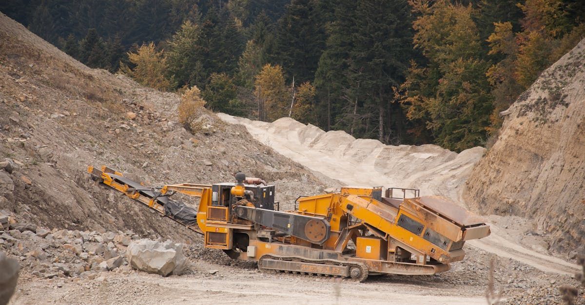 A yellow tractor is driving down a dirt road in a quarry.