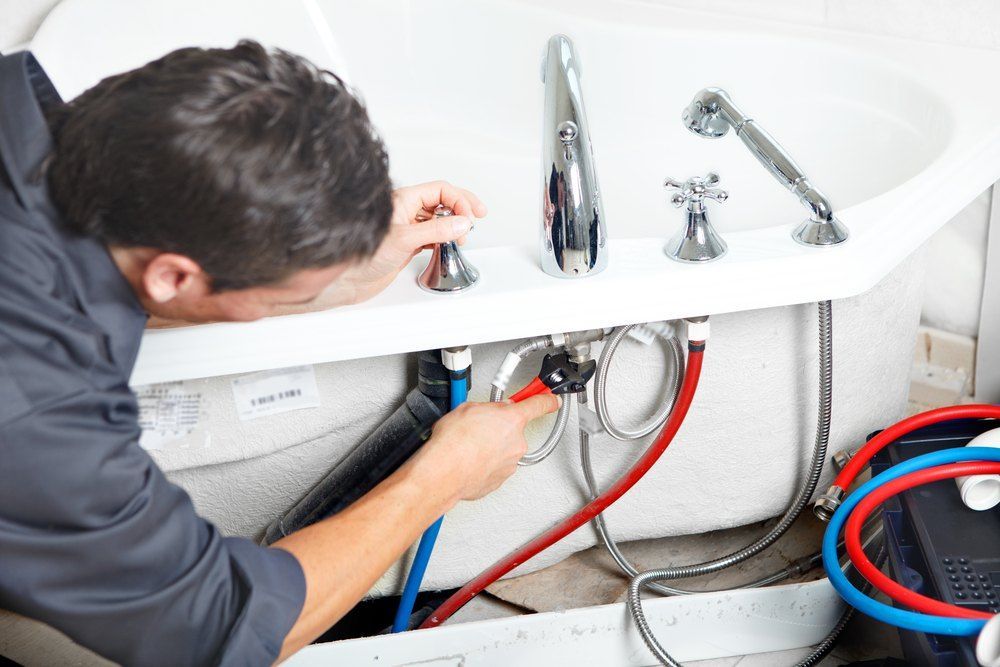 A Man is Fixing a Bathtub With a Wrench — TCP Plumbing in Tunglebung, NSW