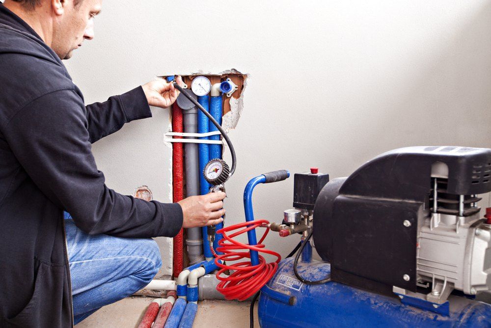 A man is working on a plumbing system with an air compressor — TCP Plumbing in Tunglebung, NSW