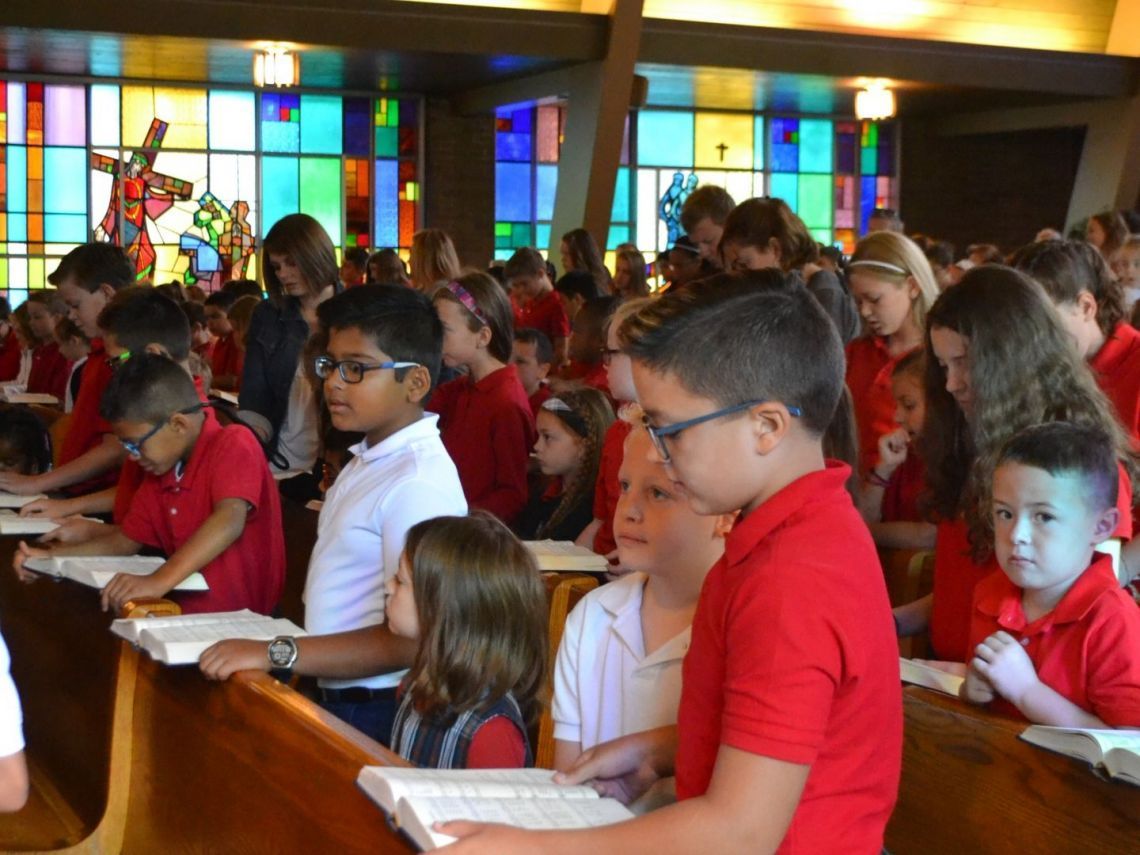 A group of children in red shirts are sitting in a church