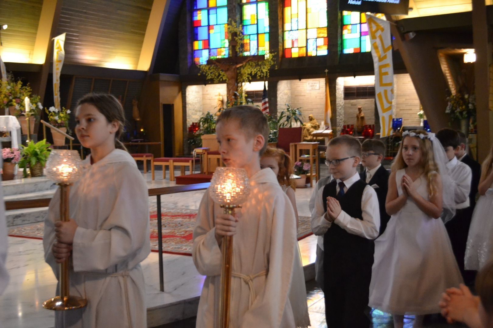 A group of children are walking through a church holding candles