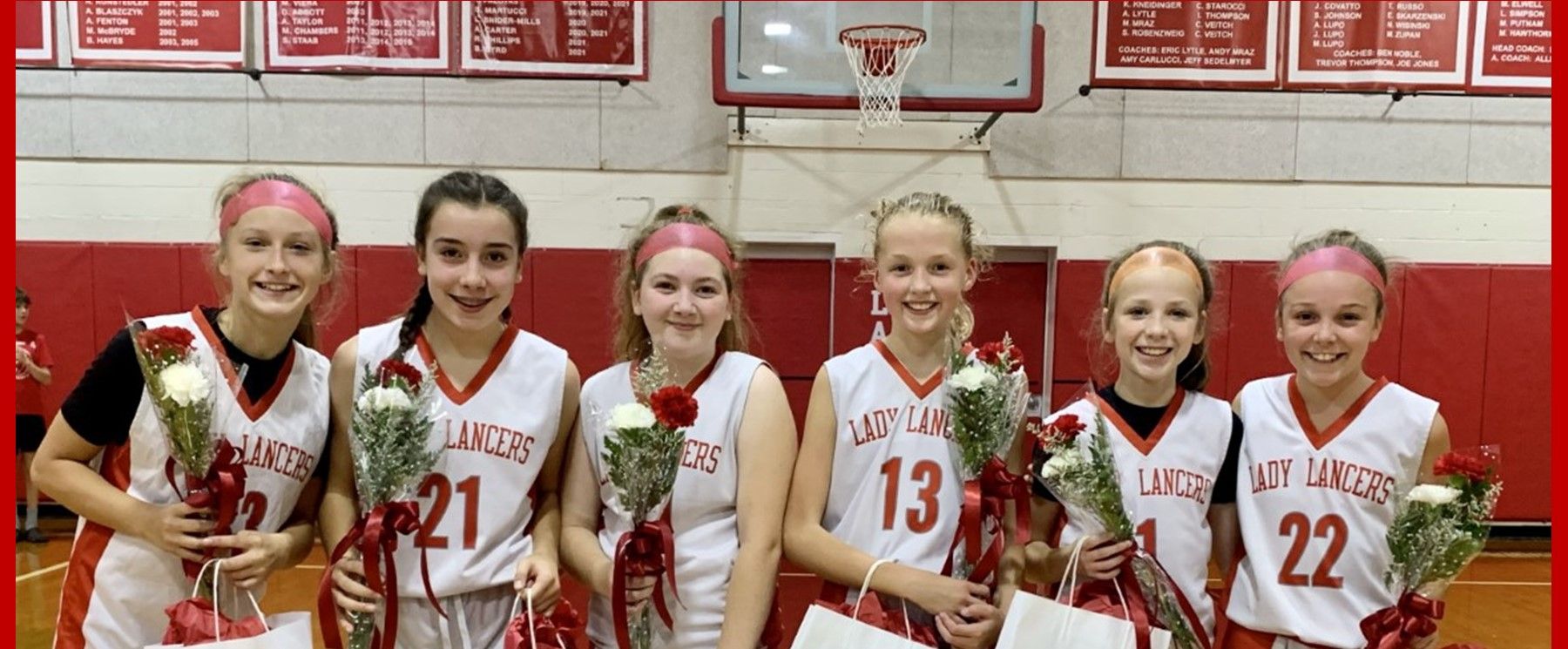 A group of girls in basketball uniforms are posing for a picture