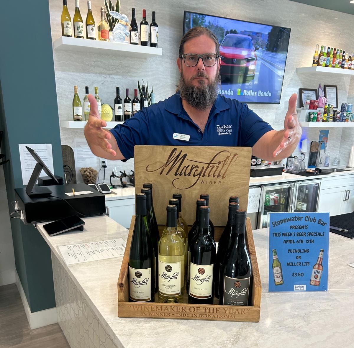 A man is standing in front of a display of wine bottles.