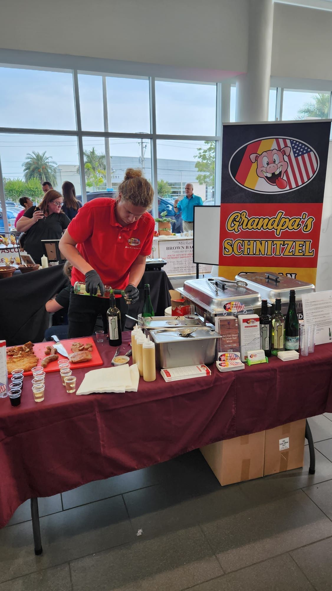 A man in a red shirt is standing at a table preparing food.