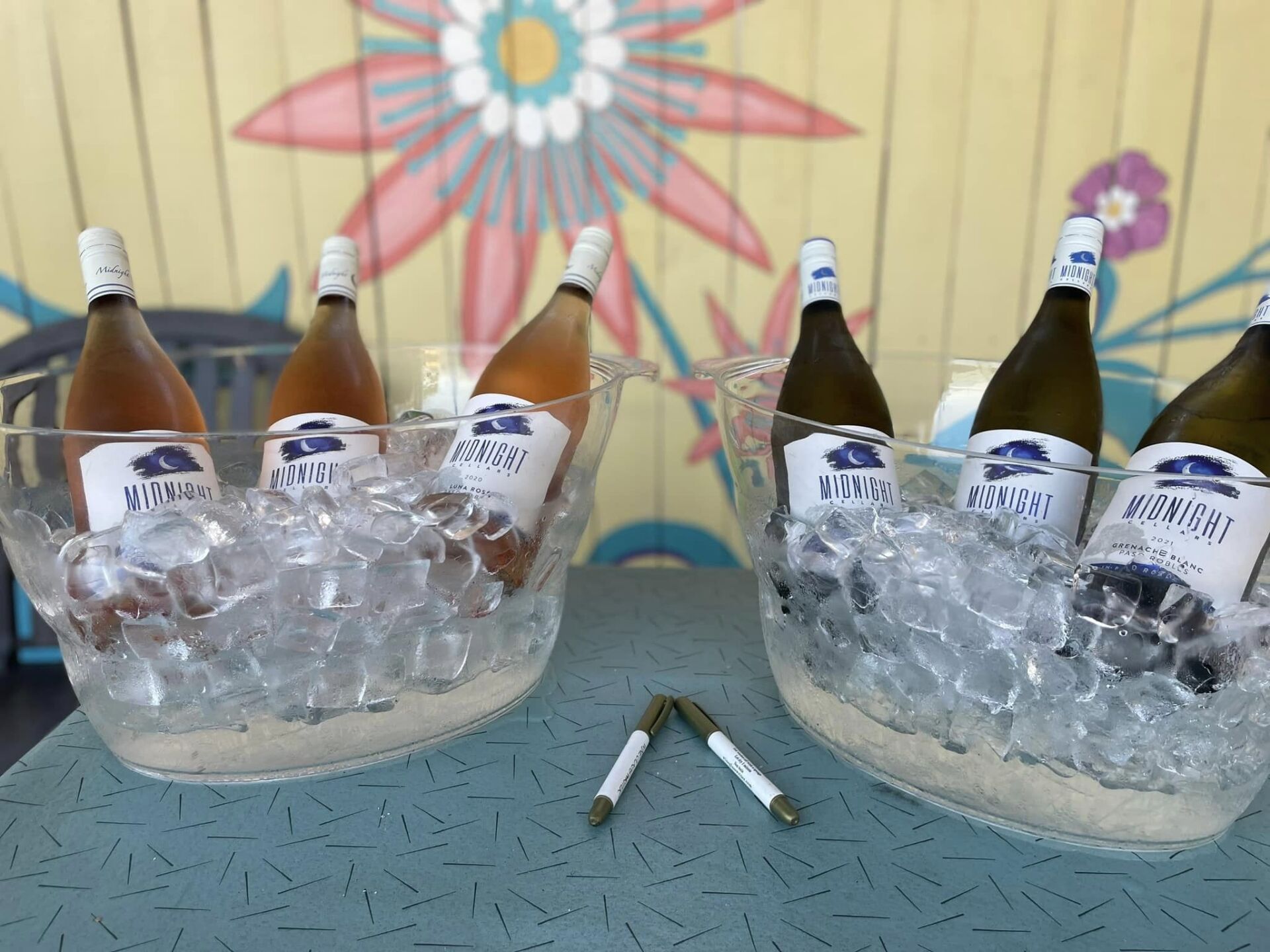 Bottles of wine are in ice buckets on a table