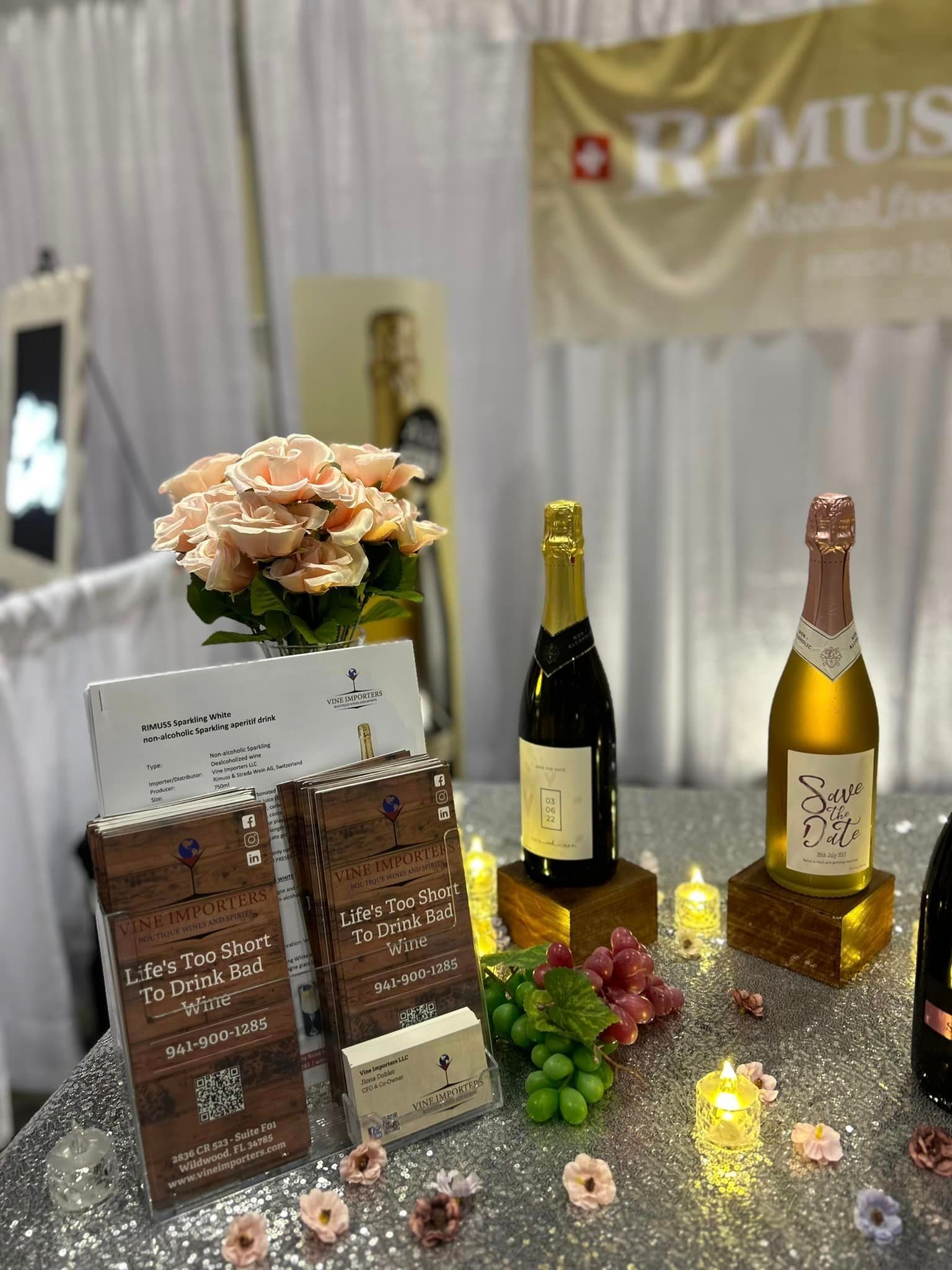 A table with bottles of wine , flowers and candles on it.
