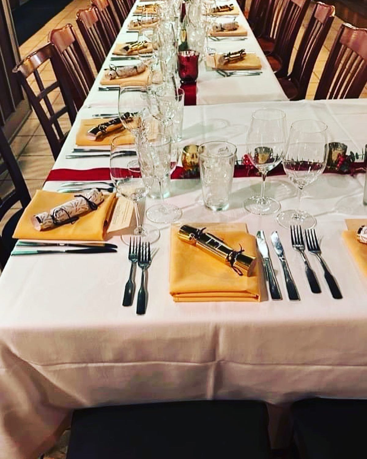 A long table set for a dinner party with wine glasses and silverware