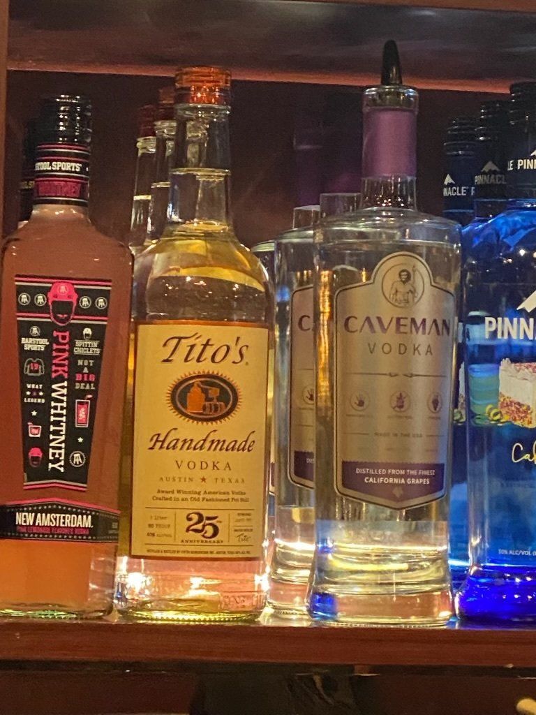 Several bottles of alcohol including tito 's and caveman vodka