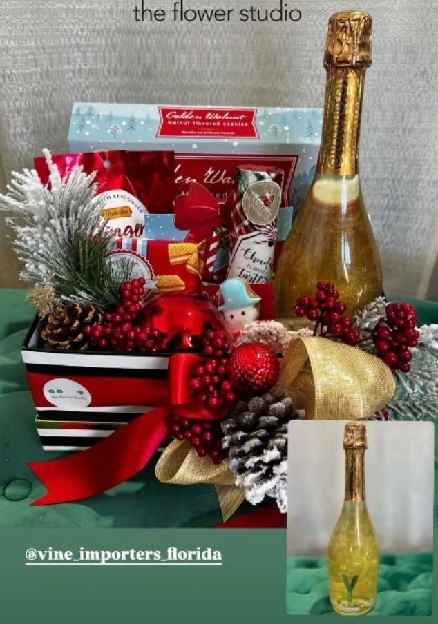A bottle of champagne is sitting on top of a christmas basket.