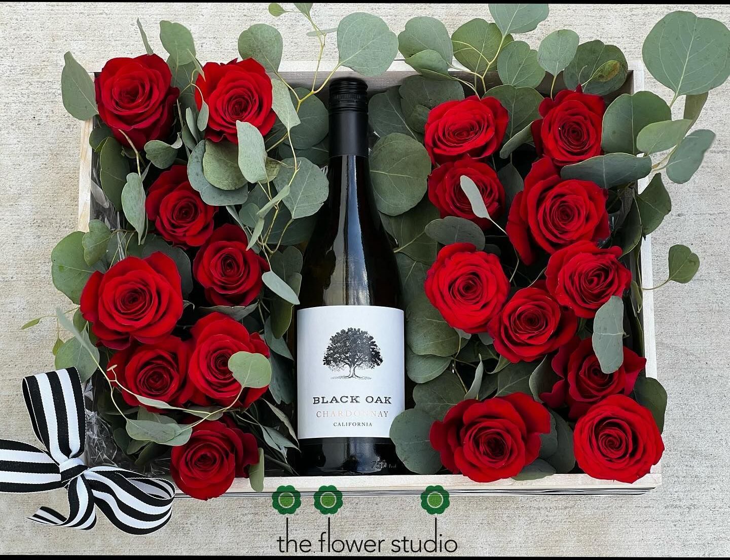 A box filled with red roses and a bottle of wine