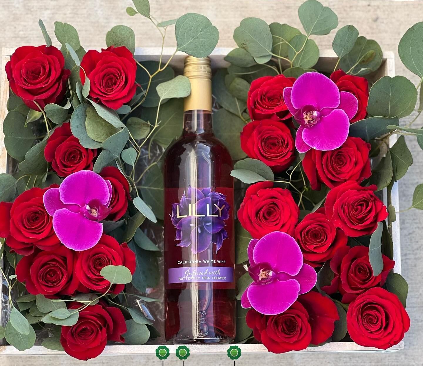 A bottle of lily wine sits in a box of red roses