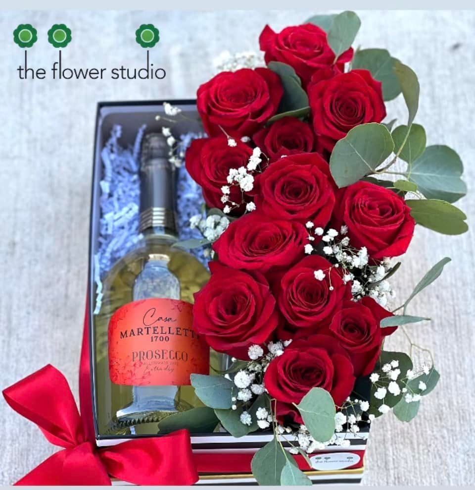 A box of red roses and a bottle of prosecco