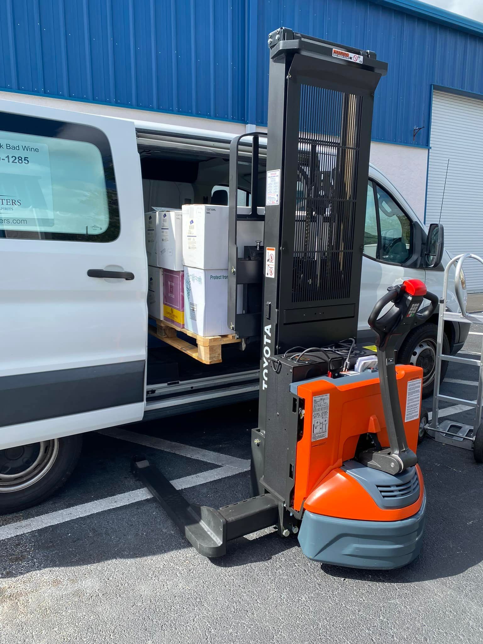 A forklift is parked in front of a white van.
