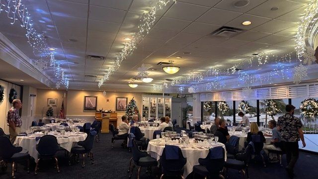 A large room filled with tables and chairs and christmas lights hanging from the ceiling.