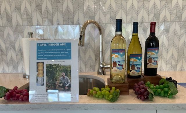 Three bottles of wine are sitting on a counter next to grapes.
