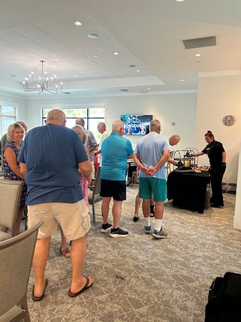 A group of people are standing in a room with their hands behind their backs.