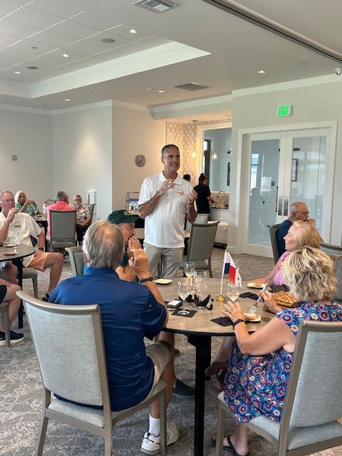 A man is talking to a group of people sitting at tables in a restaurant.