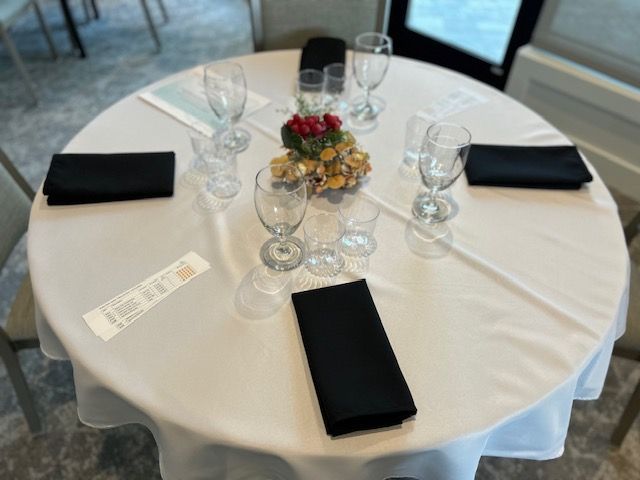 A round table with a white table cloth and black napkins