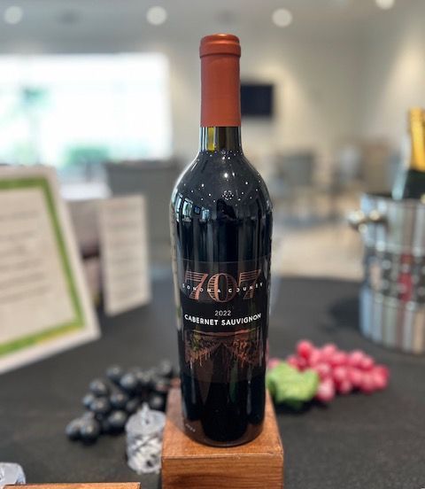A bottle of wine is sitting on a wooden block on a table.