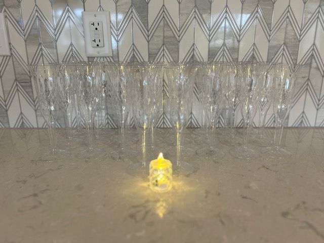 A candle is sitting on a counter next to a row of wine glasses.