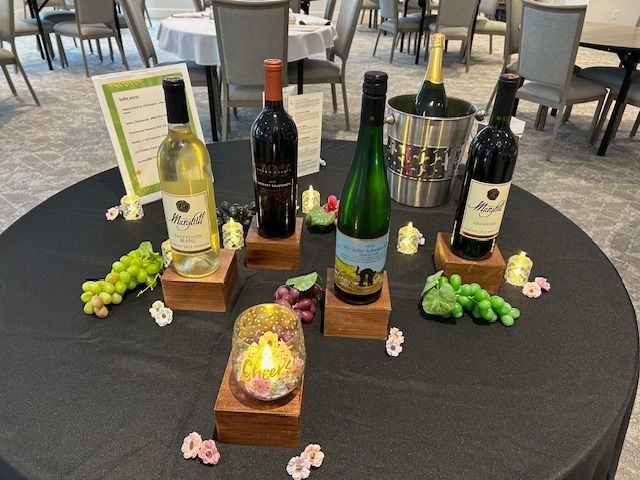 A table with bottles of wine , grapes and candles on it.