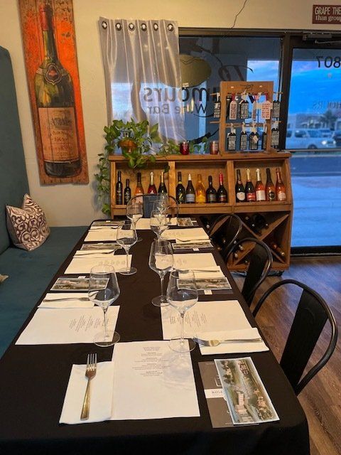 A long table with wine glasses and utensils on it