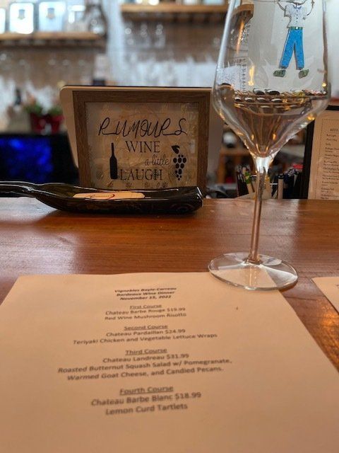 A glass of wine is sitting on a table next to a menu.