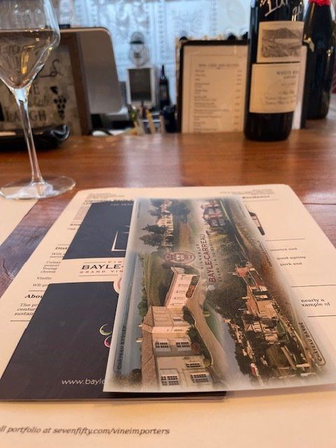 A bottle of wine sits on a table next to a menu