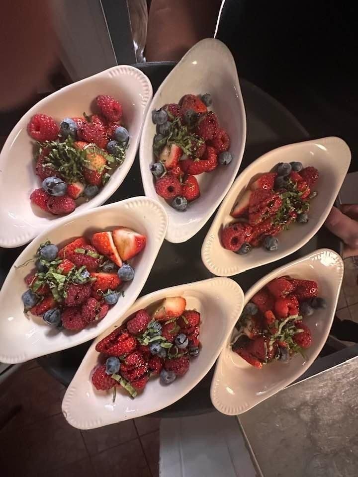 A bunch of bowls filled with strawberries and blueberries on a table.
