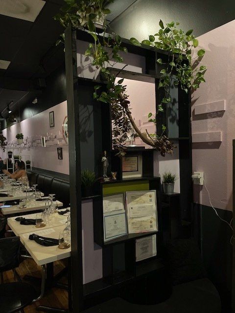 A restaurant with tables and chairs and a shelf with plants on it