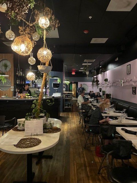 A restaurant with tables and chairs and a tree hanging from the ceiling.