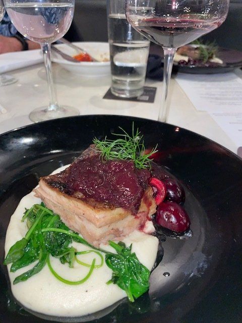 A plate of food with a glass of wine in the background